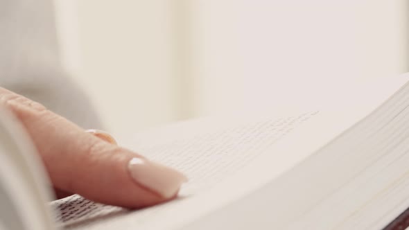 Female Reading a Book Finger Sliding on Page Close Up