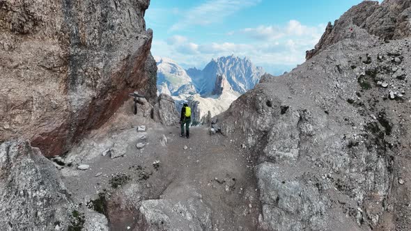 Female mountaineer with climbing gear in the Dolomites. Drone shoot revealing the valley beneath the