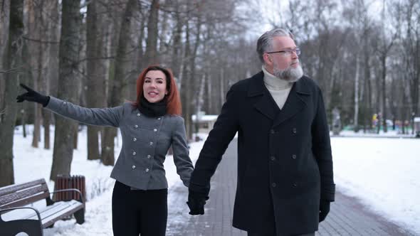 a married couple walks in the park. A young wife and a gray-haired husband