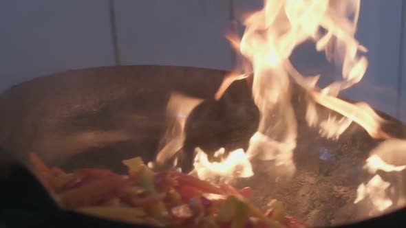 Fresh Veggies are Flambeing on a Frying Pan Over Open Fire