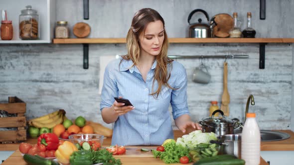 Smiling Woman Cooking Food Check Vegetables Look at Smartphone