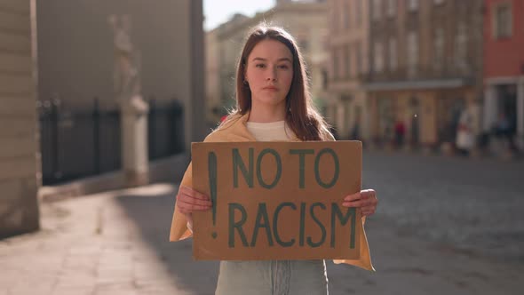 Woman Holding No to Racism Banner on City Street