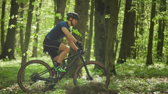 A Man on a Bicycle is Quick Passes Through a Forest Road