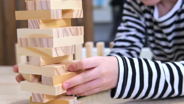 Children Playing Wooden Block Removal Tower Game at Home