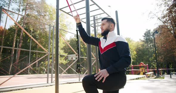 Outdoor Athletic Man Does Exercises with Elastic Band
