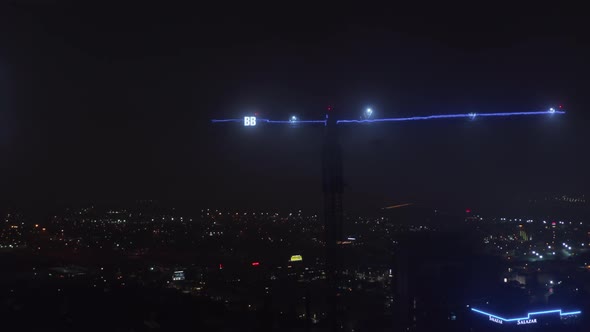 Arm of Construction Crane Illuminated with Blue Neon Light and Two Big Letters B