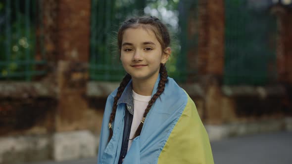 Child Girl Standing Turns Around and Raises Up the Ukrainian Flag