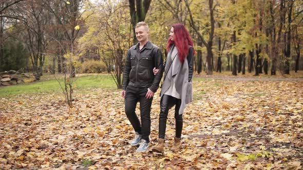 Romantic Young Couple Walking in Autumn Park During the Day Holding Hands