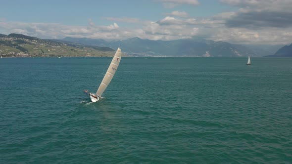 Wide Aerial of man hanging overboard on sailboat in order to steady the vessel