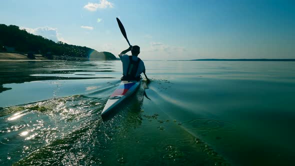 Backside View of an Oarsman Paddling Along the Water