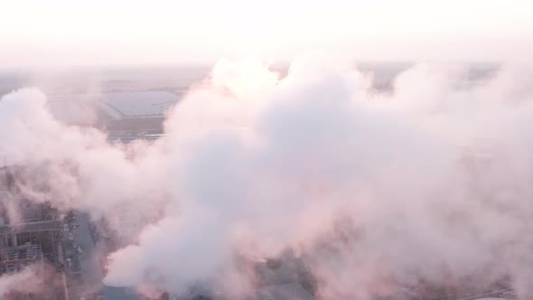 Aerial view during sunrise of steel factory powered by solar panels. Flying into the exhaust smoke