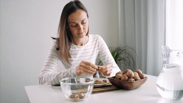 Young Woman Is Cracking a Walnuts at Domestic Room