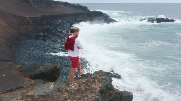 Man Observes a Magnificent Scenery of the Coast Surrounded By the Ocean Waters