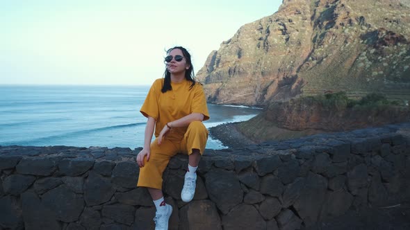 A Woman Walks Next to the Ocean Enjoying the Calm Scenery Against the Background of the Volcanic