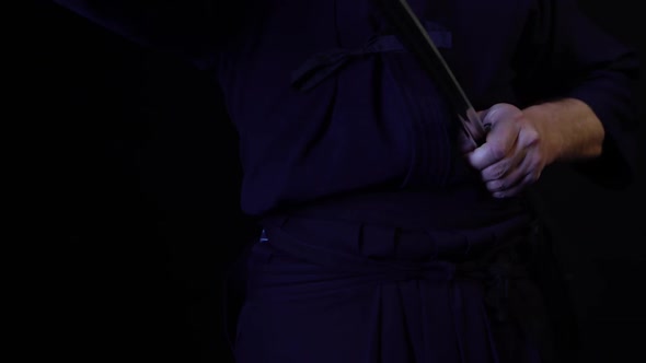 A Close-up Shot of a Ninja Man's Hand Holding a Sword and Raising It.