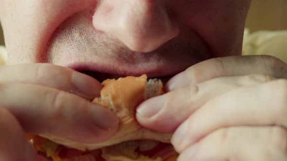 Closeup Mouth of a Hungry Man with Braces on His Teeth Greedily Bites His Hamburger Eats Hamburger