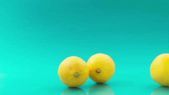 Rolling Lemons One After One on Turquoise Background