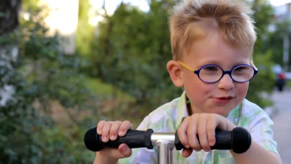 A little boy is riding a scooter.