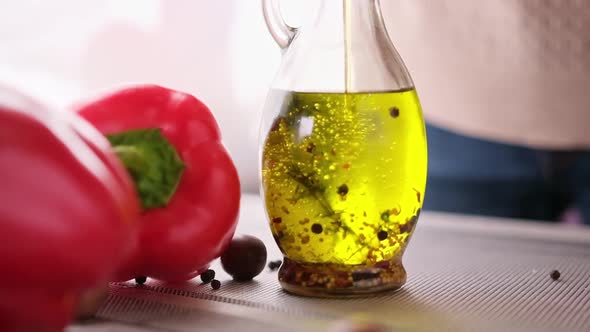 Olive Oil Pouring Down Into Glass Bottle with Herbs Slow Motion