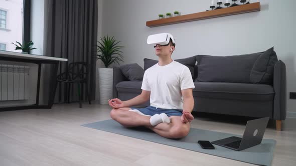 Mindfulness Cheerful Man in Virtual Reality Glasses Meditates in the Living Room Modern Technology