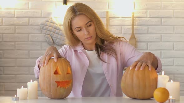 Beautiful Woman Looking at Pumpkins With Candles Inside and Showing Thumbs-Up