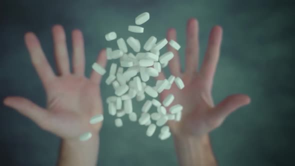 Both Hands Throwing Up Handful of Pills Above Table Surface