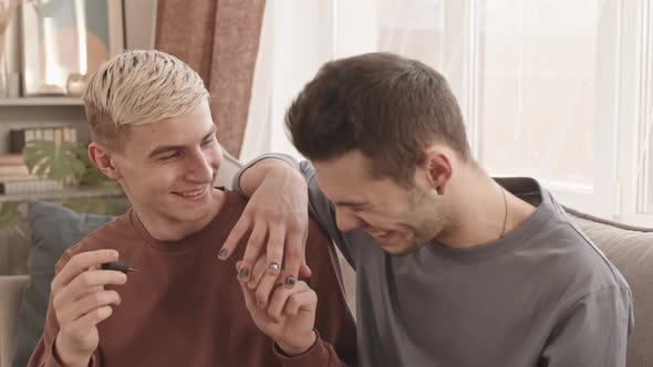 Two Young Men Applying Nail Polish and Laughing