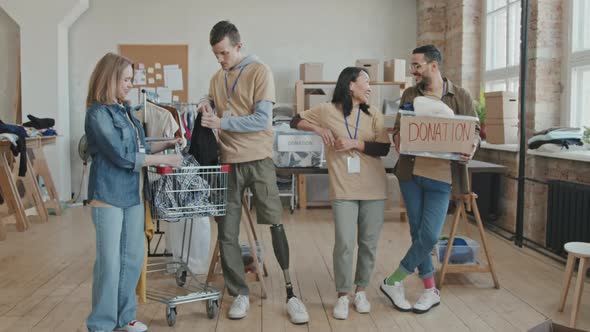 Portrait of Cheerful Volunteers Sorting out Clothes for Charity