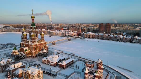 Embankment with Orthodox Church in rays of setting sun. Winter frosty evening