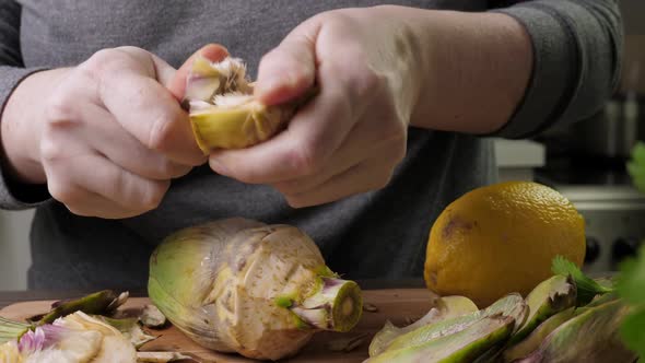 Woman Cleaning Heart of Artichokes with Spoon