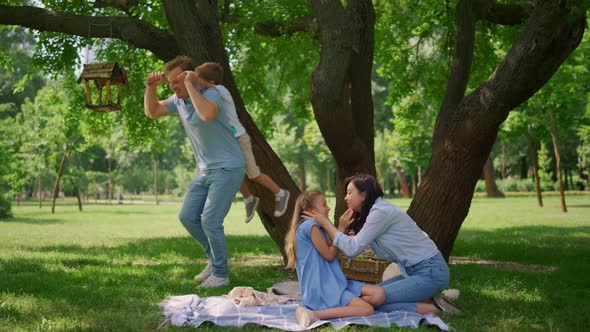 Father Hold on Back Little Son on Picnic