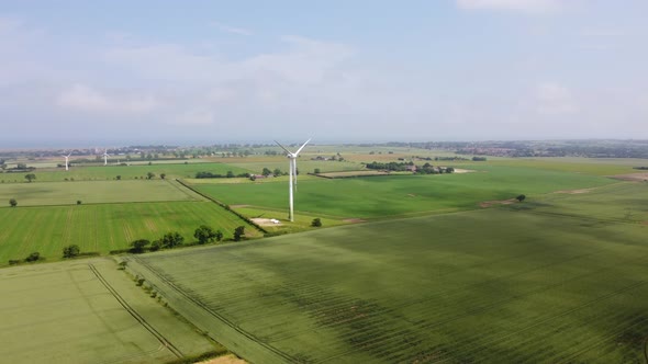 Drone Shot Flying Towards Large Wind Turbine in Open Green Fields