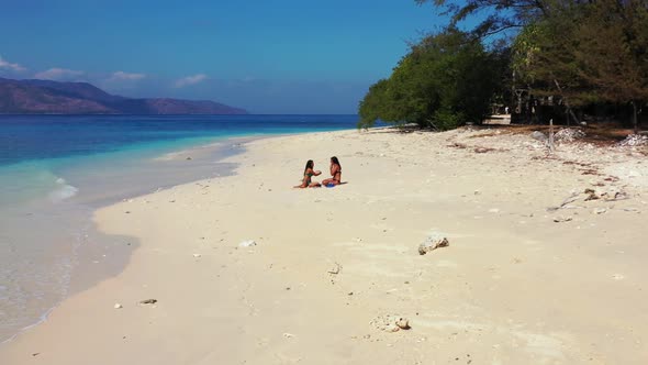 Female models happy together on marine resort beach time by turquoise sea with white sand background