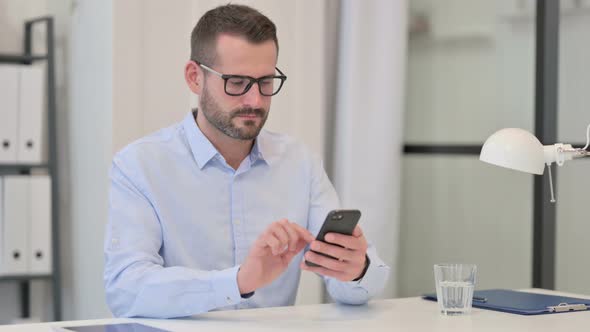 Middle Aged Man Using Smartphone at Work