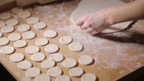 Woman molds dough at home. Roll out the dough with a rolling pin