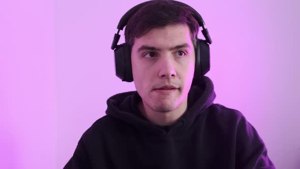 Closeup of a Man Wearing Large Wireless Headphones Playing Computer Games and Getting Emotion From