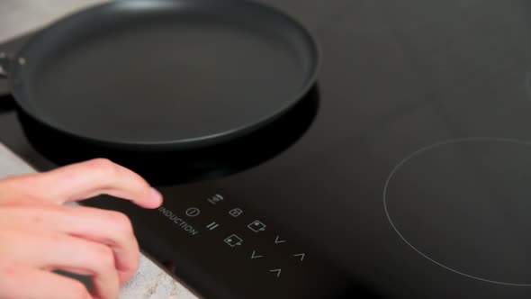 Woman Hand Turns on Modern Induction Stove in the Kitchen