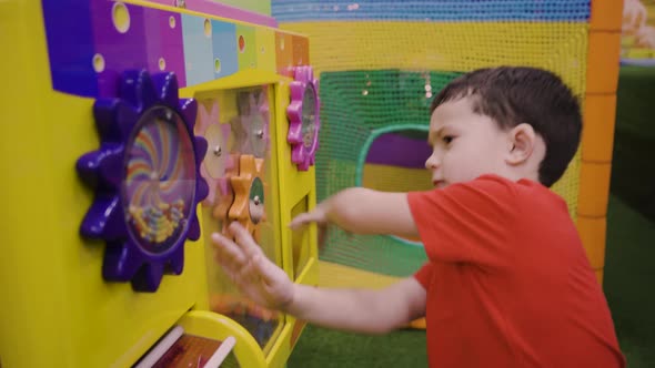 Little Brunette Boy Playing Puzzle in an Amusement Park