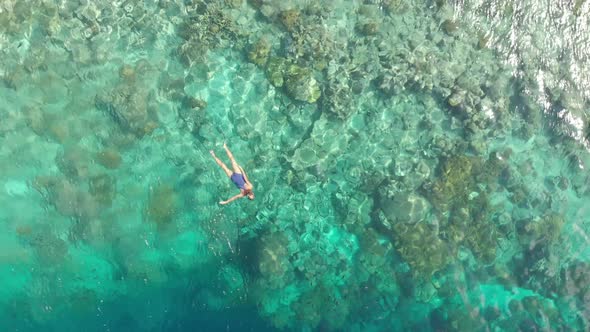 Aerial: woman snorkeling on Hatta Island coral reef tropical caribbean sea