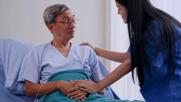 Nurse talking to elderly patient at ward