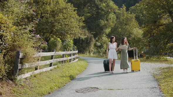 Tourists Girlfriends with Suitcases Using Paper Map