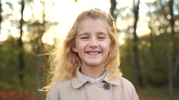 Delighted Blond Girl in Autumn Forest at Sunset