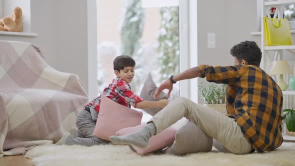 Wide Shot of Joyful Relaxed Middle Eastern Brothers Fighting Pillows in Slow Motion