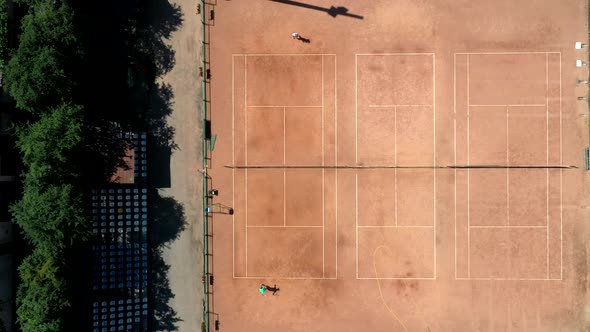 Aerial view. Players are playing tennis on orange court