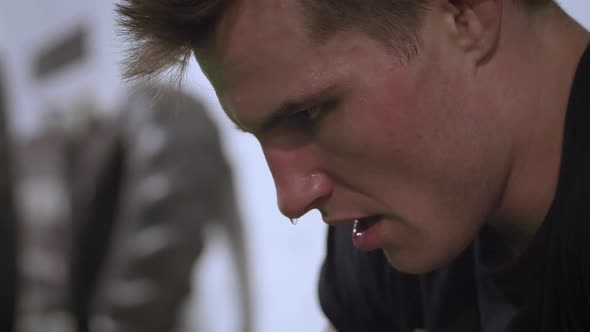 Slow motion close up of a young MMA fighter in deep focus during a training session and then looks u