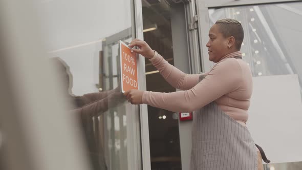 Owner Putting Raw Food Sign on Cafe Door