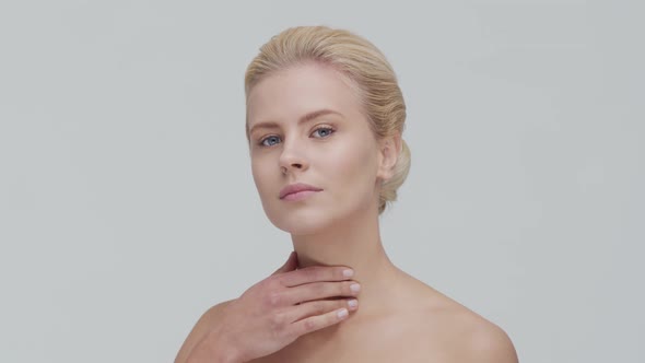 Studio portrait of young, beautiful and natural blond woman applying skin care cream. F