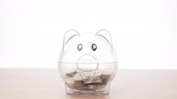 Saving money concept, Man hand putting money coin into piggy bank. Close up.