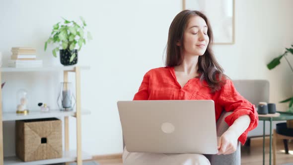 A Beautiful Young Businesswoman in a Bright Red Shirt is Typing on a Laptop