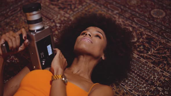 Woman With Afro Hair In Orange Dress Using Vintage 8Mm Camera